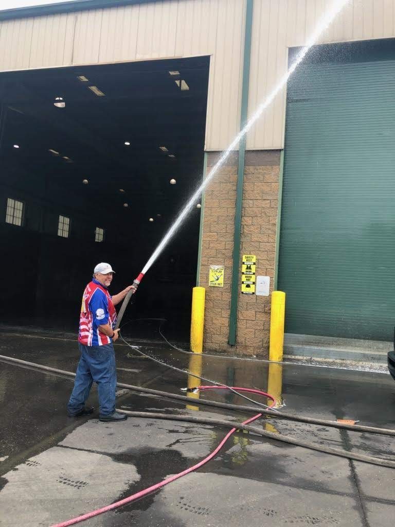Technician pressure washing a commercial building wall and loading dock