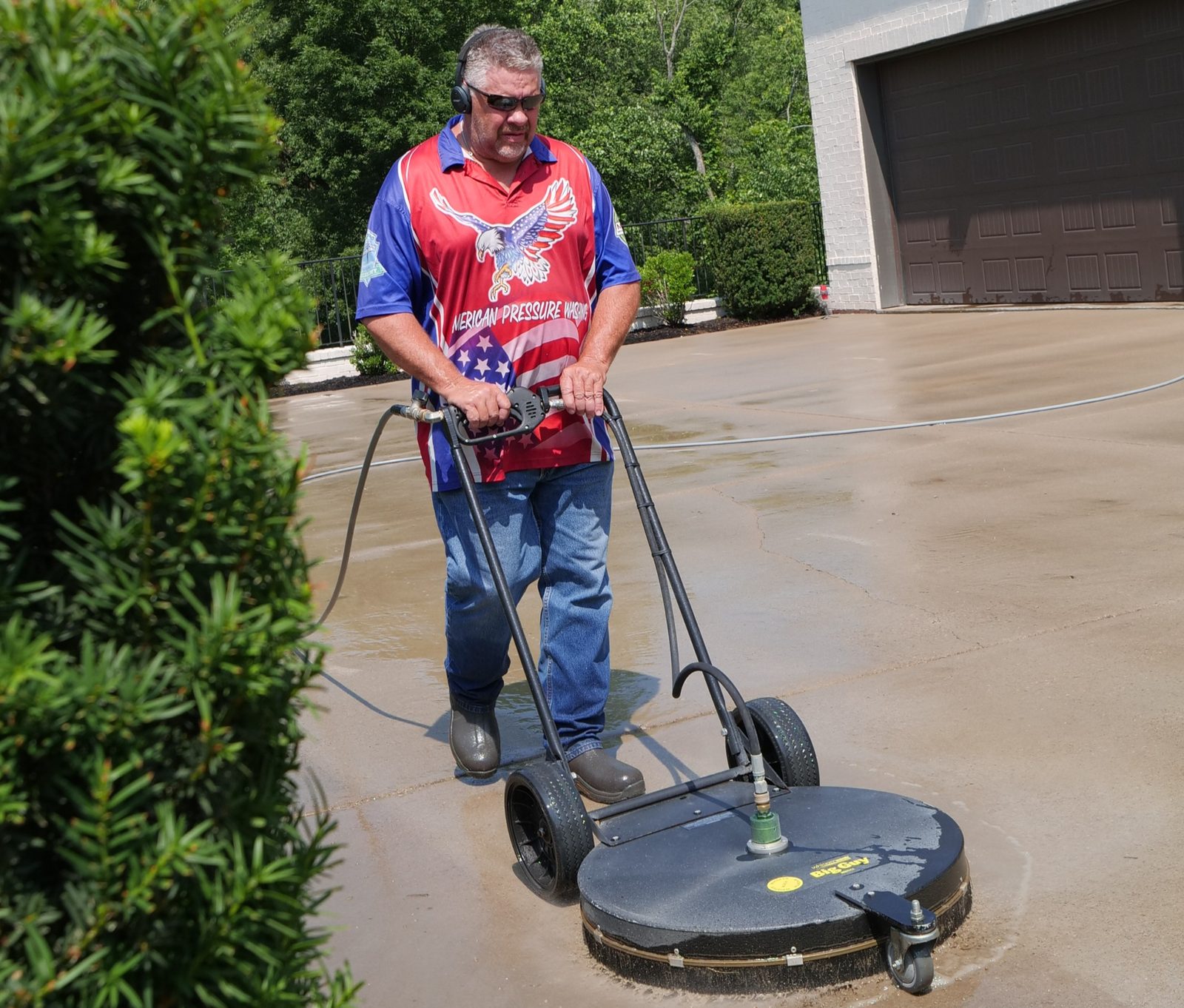 American Pressure Washing technician running a surface cleaner on a Brentwood concrete driveway